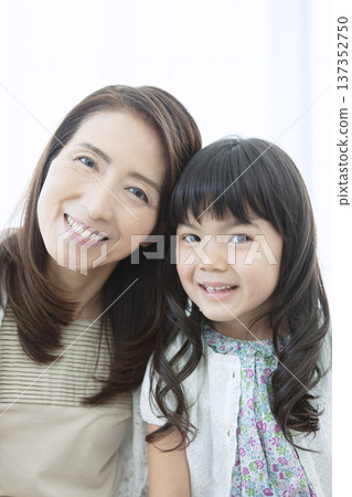 Smiling grandmother and grandchild standing close together 137352750