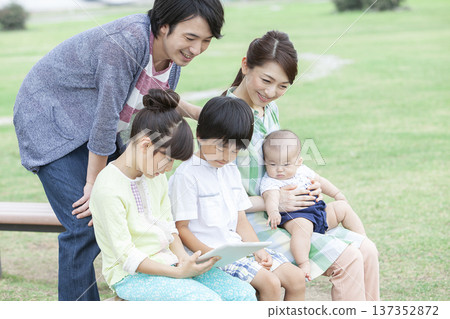 Family operating a tablet in the park Family operating a tablet in the park 137352872