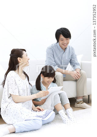 Family operating a tablet in the living room Family operating a tablet in the living room 137352952