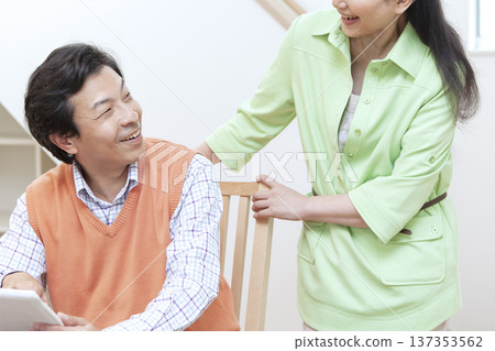 一對夫婦一邊看著平板電腦一邊聊天。 137353562