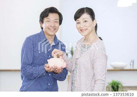 一對夫婦往存錢筒裡放錢 137353610