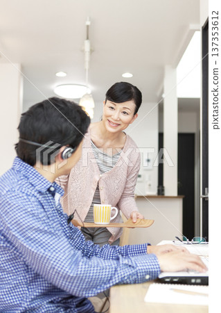 A man operating a computer and a woman carrying tea 137353612