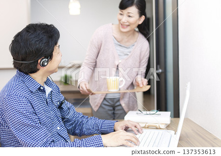 一名男子正在操作電腦，一名女子拿著茶。 137353613