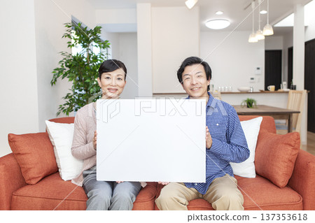 Couple holding a whiteboard on the sofa 137353618