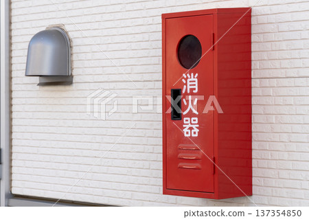 建築物牆壁上安裝著一個紅色滅火器箱。 137354850
