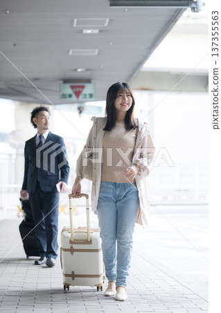 Walking woman with suitcase or carry-on bag departing at airport or transport terminal Travel transit Walking woman with suitcase or carry-on bag departing at airport or transport terminal Travel transit 137355563