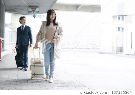 一位拖著行李箱或手提包的女士正在機場或交通樞紐候機。旅行中轉 一位拖著行李箱或手提包的女士正在機場或交通樞紐候機。旅行中轉 137355564