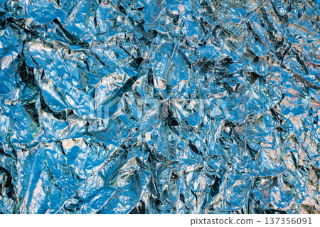 Shiny crumpled blue metallic foil reflecting light creating an abstract texture background 137356091