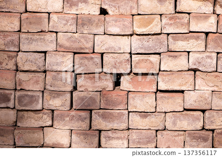 Stacked weathered common bricks forming a textured wall or pavement background 137356117