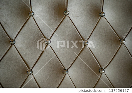 Tufted beige velvet upholstery capturing luxury and elegance with decorative buttons Tufted beige velvet upholstery capturing luxury and elegance with decorative buttons 137356127