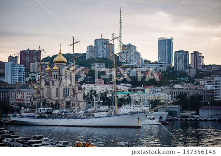 Nadezhda, a russian sail training ship, is docked in vladivostok, russia, with the city skyline and a church in the background 137356148