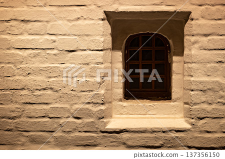 Grungy brick wall with small arched window providing old rustic architecture 137356150
