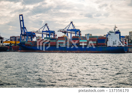Cargo vessel docked at vladivostok port, stacked multicolored containers blocking cloudy maritime skyline Cargo vessel docked at vladivostok port, stacked multicolored containers blocking cloudy maritime skyline 137356170