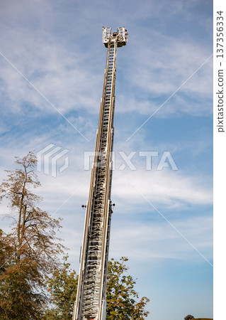 Extending aerial platform from fire engine reaching high into a blue sky 137356334