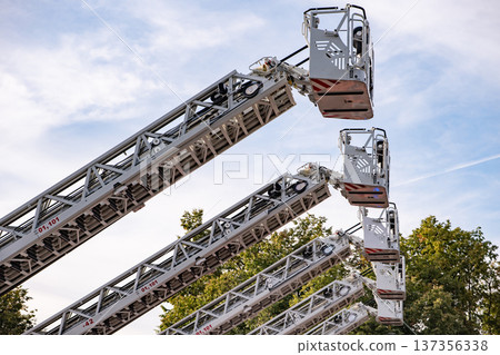Fire truck ladders extending high towards the sky during emergency service operations Fire truck ladders extending high towards the sky during emergency service operations 137356338