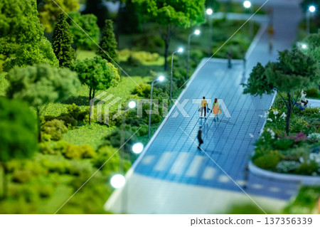 Miniature city planning model with people walking urban streets and green park area 137356339