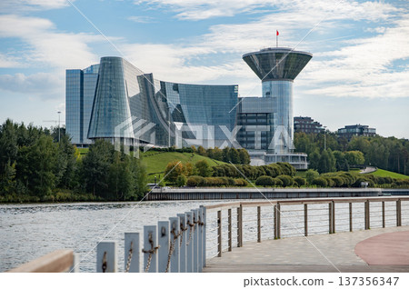 Modern government buildings with glass facades and unusual shapes standing along a riverbank in Krasnogorsk. Modern government buildings with glass facades and unusual shapes standing along a riverbank in Krasnogorsk. 137356347