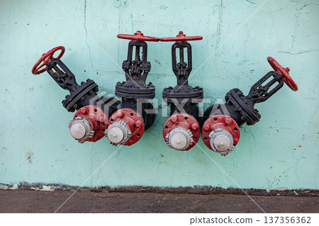 Industrial water valves with red wheels on a light green wall, providing fire safety Industrial water valves with red wheels on a light green wall, providing fire safety 137356362