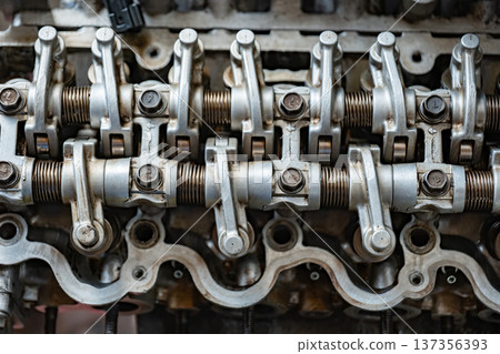 Car engine valve train closeup showing rocker arms, springs, and bolts 137356393
