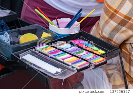 Face painting supplies showcasing vibrant rainbow cake palettes and brushes for creativity Face painting supplies showcasing vibrant rainbow cake palettes and brushes for creativity 137356537