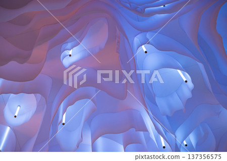 Abstract wavy fabric structure creating a glowing ethereal ceiling design Abstract wavy fabric structure creating a glowing ethereal ceiling design 137356575