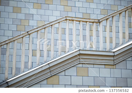 Exterior building staircase with geometric railing against a tiled wall 137356582