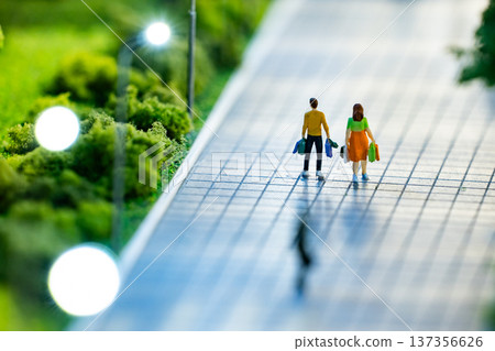 Miniature couple walking on sidewalk after shopping, carrying bags Miniature couple walking on sidewalk after shopping, carrying bags 137356626
