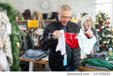 Mature male shopper selects ladies panties as a Christmas gift in fashionable clothing boutique Mature male shopper selects ladies panties as a Christmas gift in fashionable clothing boutique 137356695