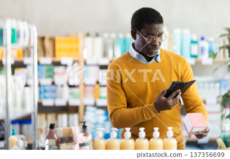 Man in glasses scans code on package of pills to check expiration date 137356699