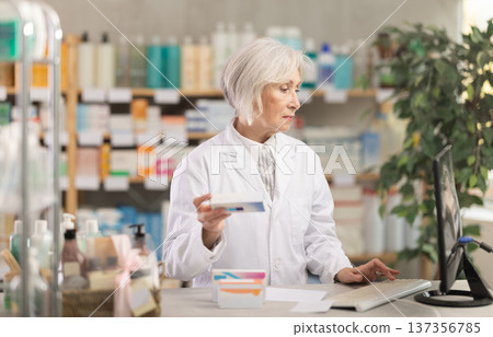 Portrait of mature female pharmacist working in a modern drugstore and offering to buy pills Portrait of mature female pharmacist working in a modern drugstore and offering to buy pills 137356785