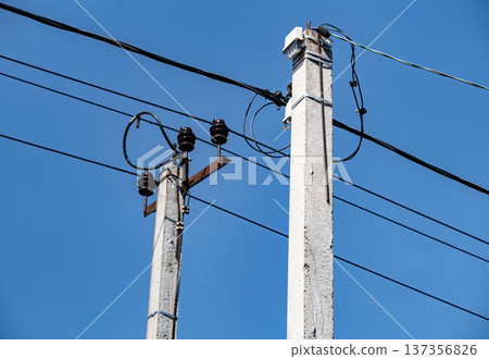 Concrete utility poles supporting power lines against a clear blue sky Concrete utility poles supporting power lines against a clear blue sky 137356826