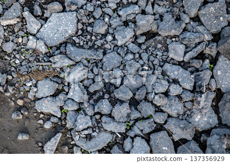 Broken asphalt pieces and gravel on the ground, creating a rough texture 137356929