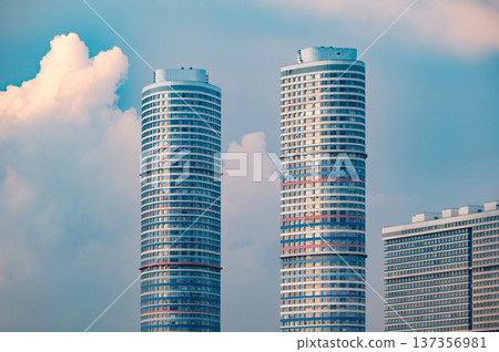Modern city skyline with two tall residential skyscrapers reaching up to blue sky Modern city skyline with two tall residential skyscrapers reaching up to blue sky 137356981
