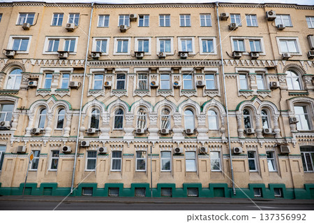 Ornate historic building facade featuring numerous windows and air conditioners Ornate historic building facade featuring numerous windows and air conditioners 137356992