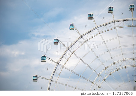 Ferris wheel observation pods against a blue cloudy sky at an amusement park Ferris wheel observation pods against a blue cloudy sky at an amusement park 137357006