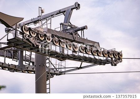 Metal ski lift tower and wheels supporting heavy cables against a clear sky Metal ski lift tower and wheels supporting heavy cables against a clear sky 137357015