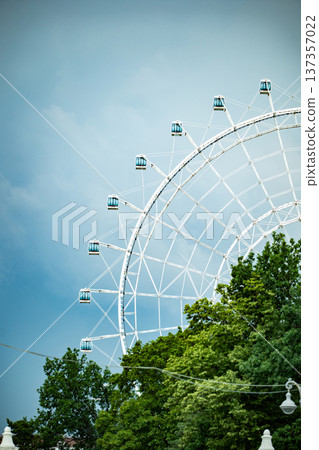 Ferris wheel against a cloudy sky offering city views and amusement park fun Ferris wheel against a cloudy sky offering city views and amusement park fun 137357022