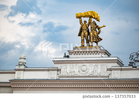 Worker and collective farm woman golden statue on VDNKh Pavilion against sky 137357033