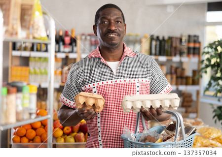 Adult man choosing eggs in grocery store Adult man choosing eggs in grocery store 137357034