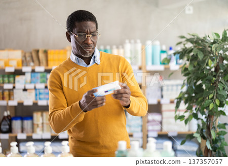 Focused customer choosing therapeutic ointment in pharmacy Focused customer choosing therapeutic ointment in pharmacy 137357057