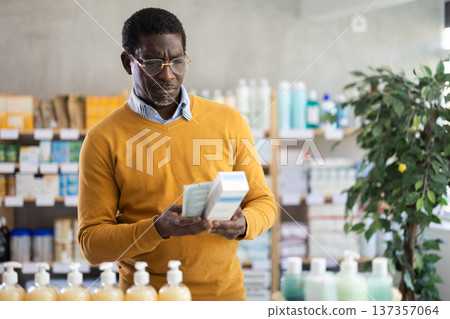 African man buyer select cream in drug store African man buyer select cream in drug store 137357064