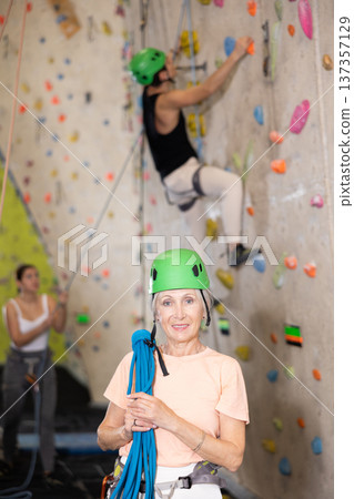 Senior confident female climber with her equipment getting ready for training 137357129