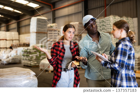 Man and women working in warehouse, discussing job Man and women working in warehouse, discussing job 137357183