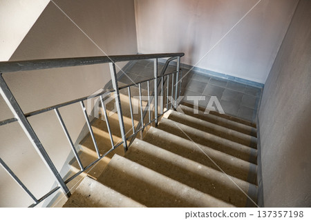 Concrete staircase leading down with metal handrail and sun shadows Concrete staircase leading down with metal handrail and sun shadows 137357198