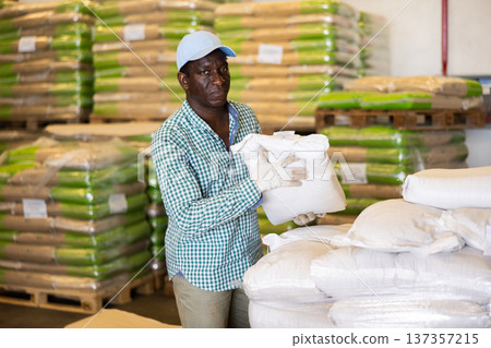 Man working in warehouse, lifting heavy bag Man working in warehouse, lifting heavy bag 137357215