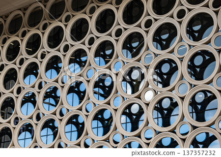 Modern building facade featuring abstract circular pattern and glass windows Modern building facade featuring abstract circular pattern and glass windows 137357232