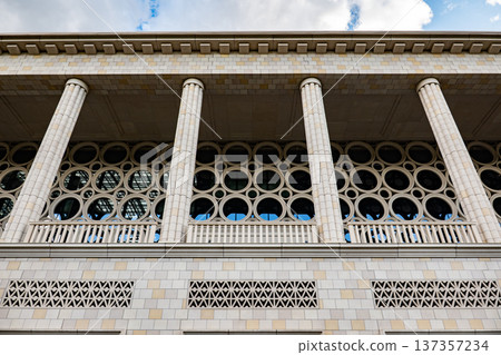 Modernist building facade featuring classical columns and geometric circular windows Modernist building facade featuring classical columns and geometric circular windows 137357234