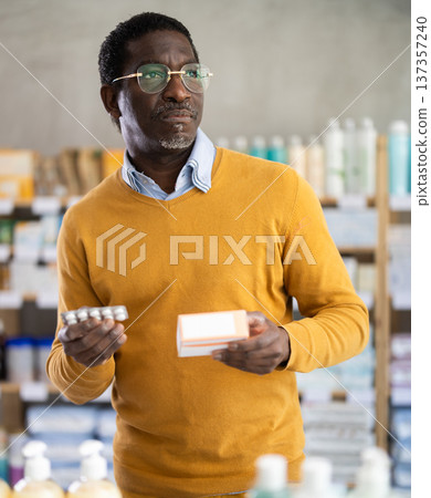 Adult man chooses pills at pharmacy 137357240