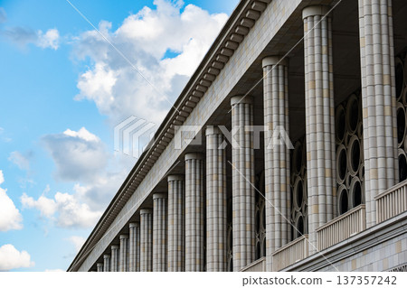 Architectural facade presenting symmetry and classical columns against a blue sky Architectural facade presenting symmetry and classical columns against a blue sky 137357242