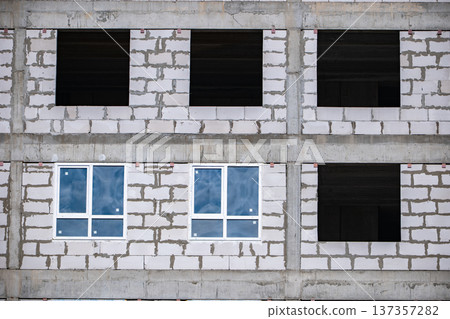 Building under construction with new windows installed on a modern facade Building under construction with new windows installed on a modern facade 137357282
